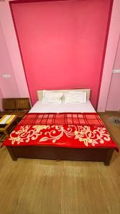 a bedroom with a red and white bed with a pink wall at Hotel Ashirwad in Chhatarpur