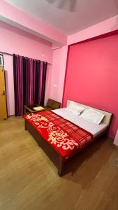 a bedroom with a large bed with a pink wall at Hotel Ashirwad in Chhatarpur