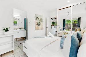 a white bedroom with two beds and a mirror at Green Cottage Trinity Beach Pet friendly BBQ in Trinity Beach