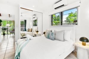 a white bedroom with a bed and a mirror at Green Cottage Trinity Beach Pet friendly BBQ in Trinity Beach +32 photos