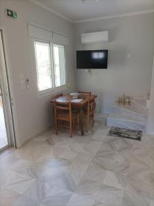 a dining room with a table and a television on the wall at Betty's Seaside Olive House in Ofrínion