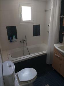 a bathroom with a toilet and a tub and a sink at Betty's Seaside Olive House in Ofrínion +19 photos