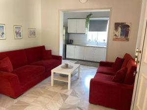 a living room with two red couches and a table at Betty's Seaside Olive House in Ofrínion