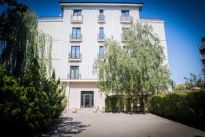 a white building with a tree in front of it at Hotel Imperial Timisoara by JR in Timişoara