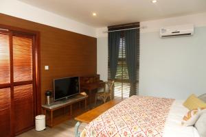 a bedroom with a bed and a desk with a television at Shell Villa apartel resort in Koror