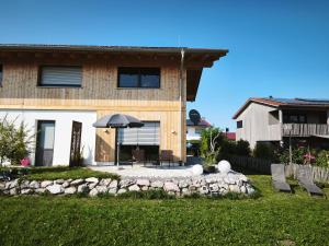 a house with an umbrella and chairs in a yard at Ferienwohnung im Panoramaweg in Rieden