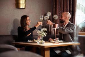 a man and woman sitting at a table with glasses of wine at Hotel Paganella Andalo in Andalo