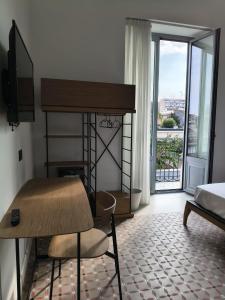 ein Schlafzimmer mit Schreibtisch, Bett und Balkon in der Unterkunft Hotel Pietranera in Catania