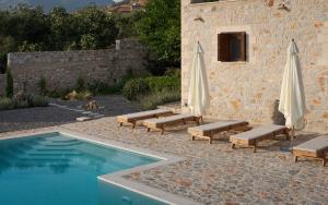 a pool with chairs and umbrellas next to a building at Pirgos Petropoulea in Poliána