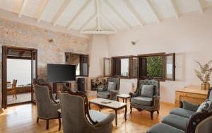 a living room with chairs and a flat screen tv at Pirgos Petropoulea in Poliána