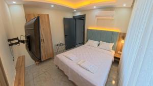 a bedroom with a bed and a flat screen tv at Hillfort Suites Apart Otel in Demre