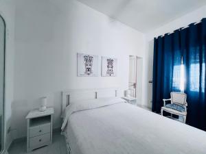 a white bedroom with a large bed and a chair at Le casette di nonna Giulia B in Lingua