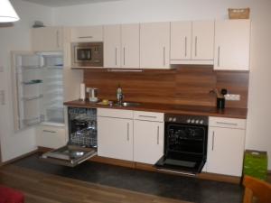 شقة أندي في واغراين: مطبخ بدولاب بيضاء ومغسلة وثلاجة