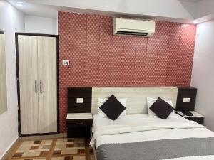 a bedroom with a bed and a red wall at Grand Almada Inn in Lucknow