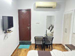 a room with two chairs and a door with a tv at Grand Almada Inn in Lucknow