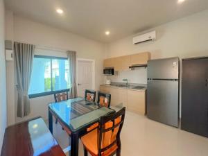 a kitchen with a table and a stainless steel refrigerator at Indigo Garden Villa by Somjai in Ban Tha Fat