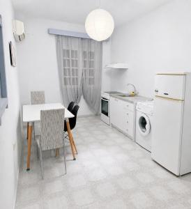 a white kitchen with a table and a washing machine at Galatas home in Galatas