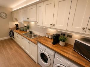 a kitchen with white cabinets and a washer and dryer at The Viking Townhouse - Heart of Waterford in Waterford