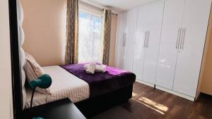 a bedroom with a bed with purple sheets and a window at Khopolong Estates in Berea Hills