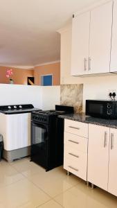 a kitchen with black appliances and white cabinets at Khopolong Estates in Berea Hills