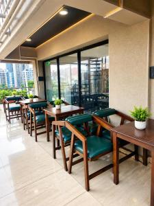 a restaurant with wooden tables and green chairs at Hotel Pune Grand in Pune +6 photos
