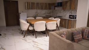 a kitchen with a wooden table and white chairs at Murree best apartment in Murree