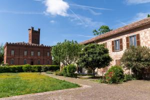 an old brick building with a clock tower in the background at Uviglie Apartments in Rosignano Monferrato