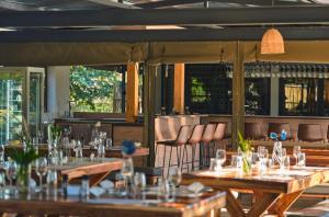 a restaurant with wooden tables and chairs and windows at Omulunga Bush Camp in Ruacana
