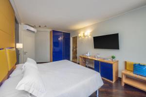 a bedroom with a bed and a desk and a tv at Garda Suite Hotel - Tonelli Hotels in Riva del Garda