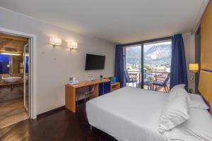 a hotel room with a bed and a desk and a window at Garda Suite Hotel - Tonelli Hotels in Riva del Garda