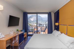 a hotel room with a bed and a desk and a window at Garda Suite Hotel - Tonelli Hotels in Riva del Garda