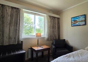 a room with a bed and a chair and a table and a window at Idrettsparken in Røros