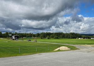 a field with a fence and a house in the distance at Idrettsparken in Røros +6 photos
