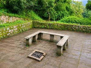 a wooden bench sitting in a courtyard next to a stone wall at AKS Cottage in Yercaud