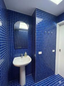 a blue tiled bathroom with a sink and a mirror at The Bluff Shack in Wye River
