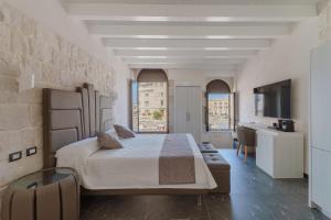 a bedroom with a large bed and a desk at La Finestra sul Mare di Ortigia Suite Luxury in Syracuse