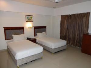a hotel room with two beds and a window at The Kunnathan Residency in Perumpāvūr