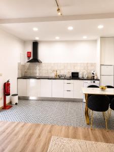 a kitchen with white cabinets and a table at Mirando Espanha in Melgaço