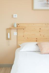 a bedroom with a white bed with a wooden headboard at Hotel Bistrot FINE in Anglet +57 photos