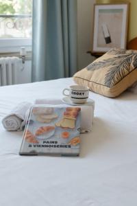 a magazine sitting on a bed with a cup of coffee at Hotel Bistrot FINE in Anglet
