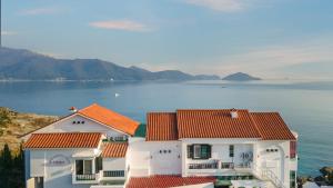 two white houses with orange roofs next to the water at Namhae Opera House Pension in Namhae