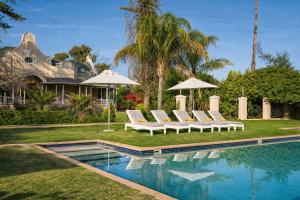 a house with a swimming pool with chairs and umbrellas at Bakenskraal Ostrich Palace in Oudtshoorn