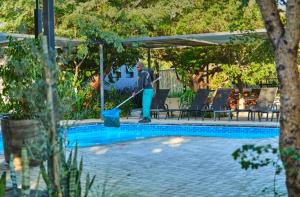a man is cleaning a swimming pool with amop sidx sidx sidx at Omulunga Bush Camp in Ruacana