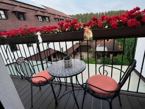 a balcony with a table and chairs and flowers at Apartmány Sladký sen in Kežmarok