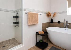 a white bathroom with a tub and a shower at Nine on Uys street B & B in Jeffreys Bay +45 photos
