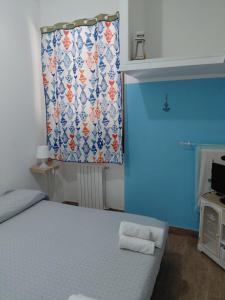 a blue room with a bed with a window with a curtain at Il Gelso Casa Vacanze in Piombino