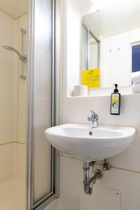 a bathroom with a sink and a mirror at SLEEEP Hotel Sattledt in Sattledt +29 photos