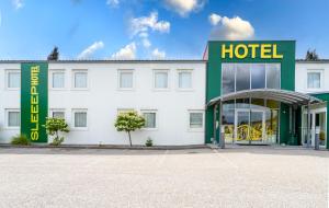 a hotel with a white building with a green and yellow sign at SLEEEP Hotel Sattledt in Sattledt
