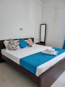 a large bed with blue and white sheets and pillows at Wings Hotel & Hostel in Trincomalee
