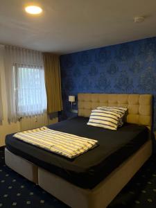 a bedroom with a large bed with a blue wall at WaldGold Aparthotel in Nagold